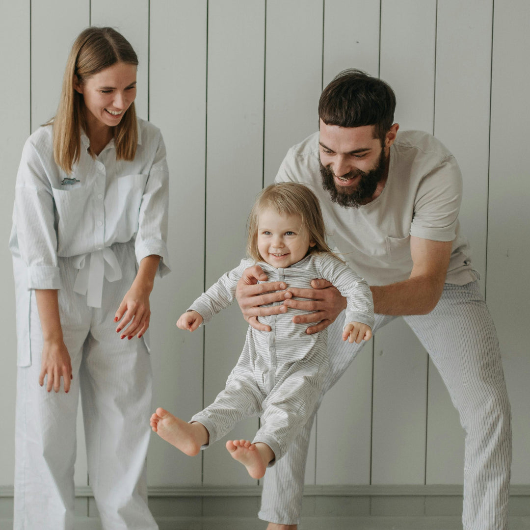 Famille jouant avec un enfant souriant, représentant un moment heureux pendant l’apprentissage de la propreté.